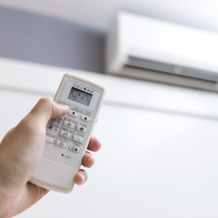 Close-up of men hand operating air conditioner with remote control
